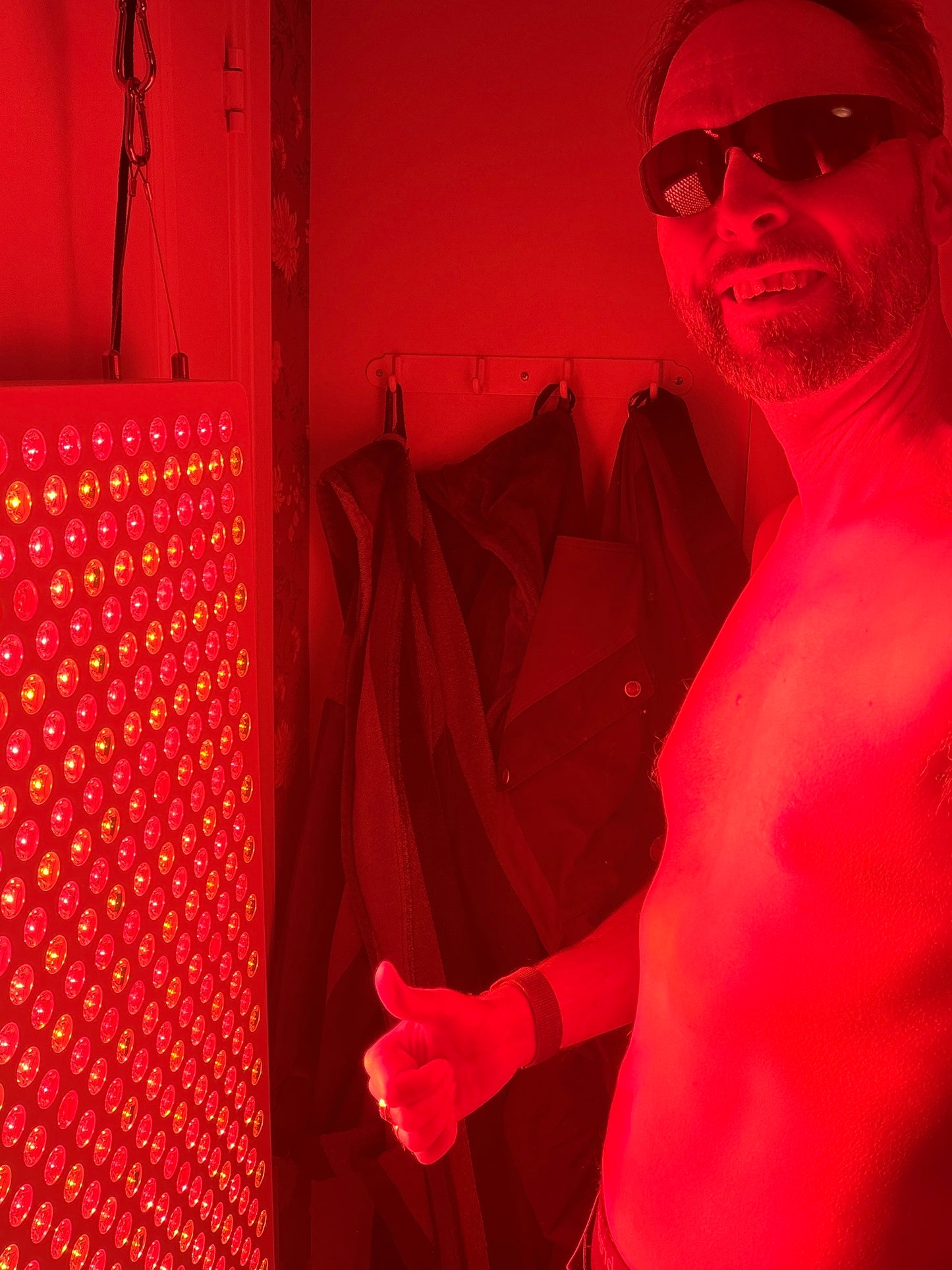 Person står lugnt framför rödljuspanel i Hälsostugan – mjuk återhämtning utan prestation
